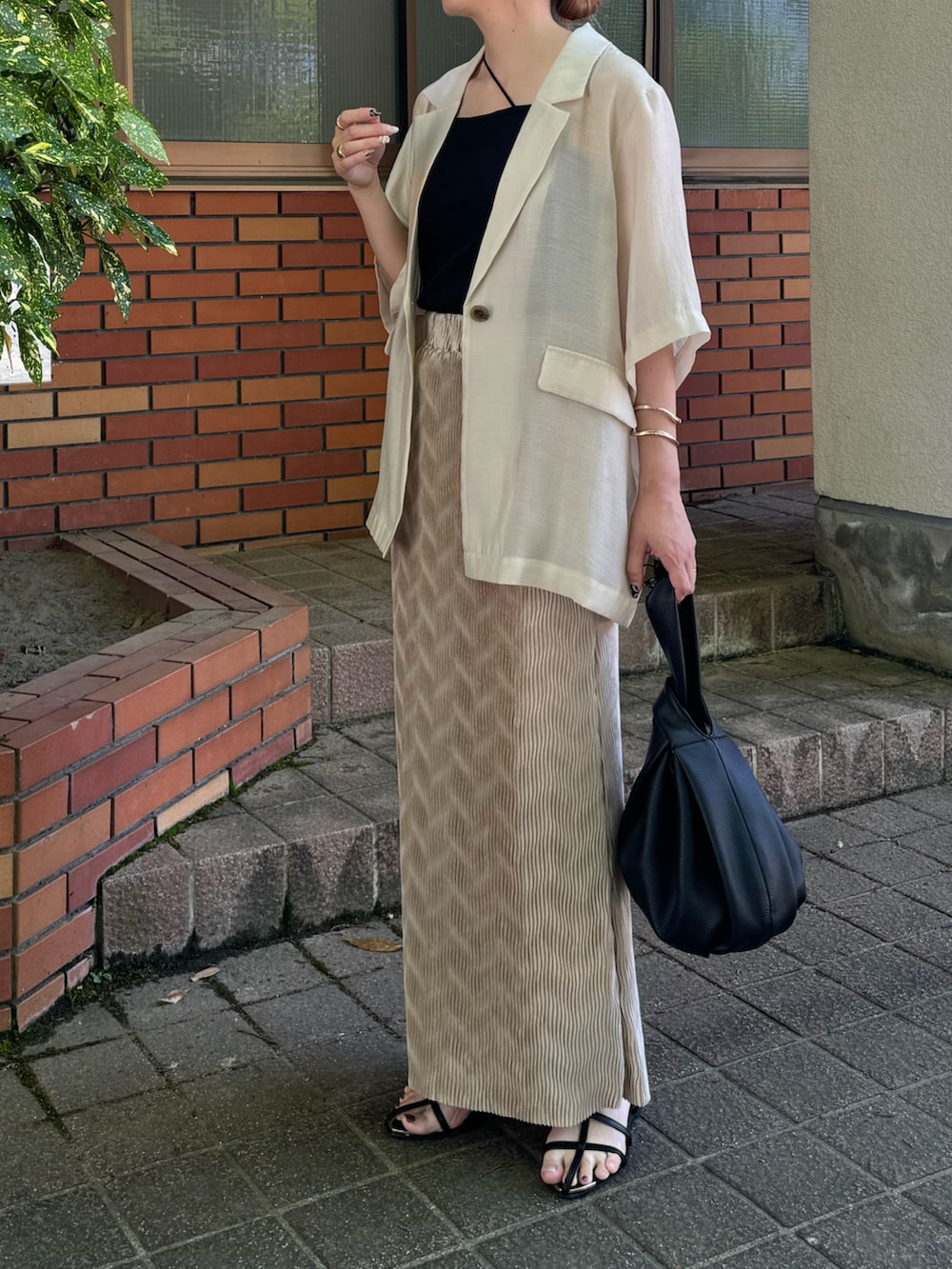 ホワイト系のテーラードジャケット、ブラック系のサンダル、ブラック系のハンドバッグを着用したレディースの夏コーディネートの5枚目の写真