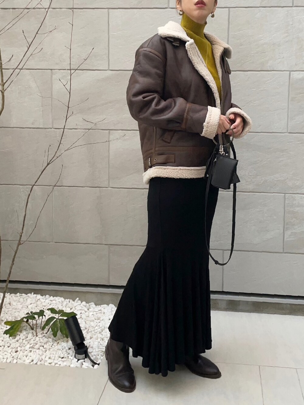 ブラウン系のブルゾン、グリーン系のニット/セーター、ブラック系のショルダーバッグを着用したレディースの秋コーディネートの3枚目の写真