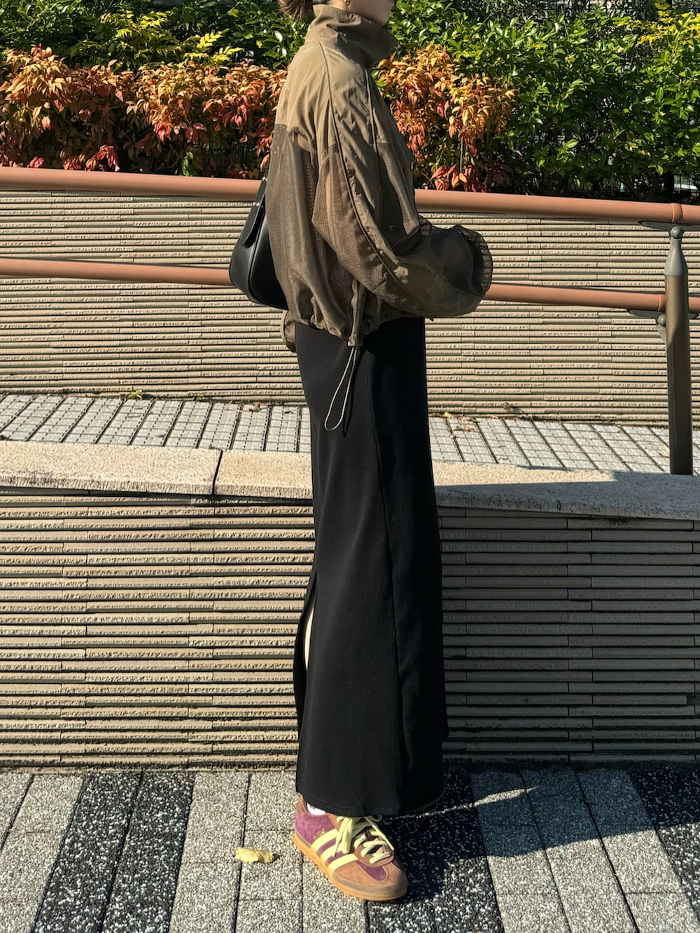 レッド系のスニーカー、ブラック系のハンドバッグ、ブラック系のワンピースを着用したレディースの秋コーディネートの3枚目の写真