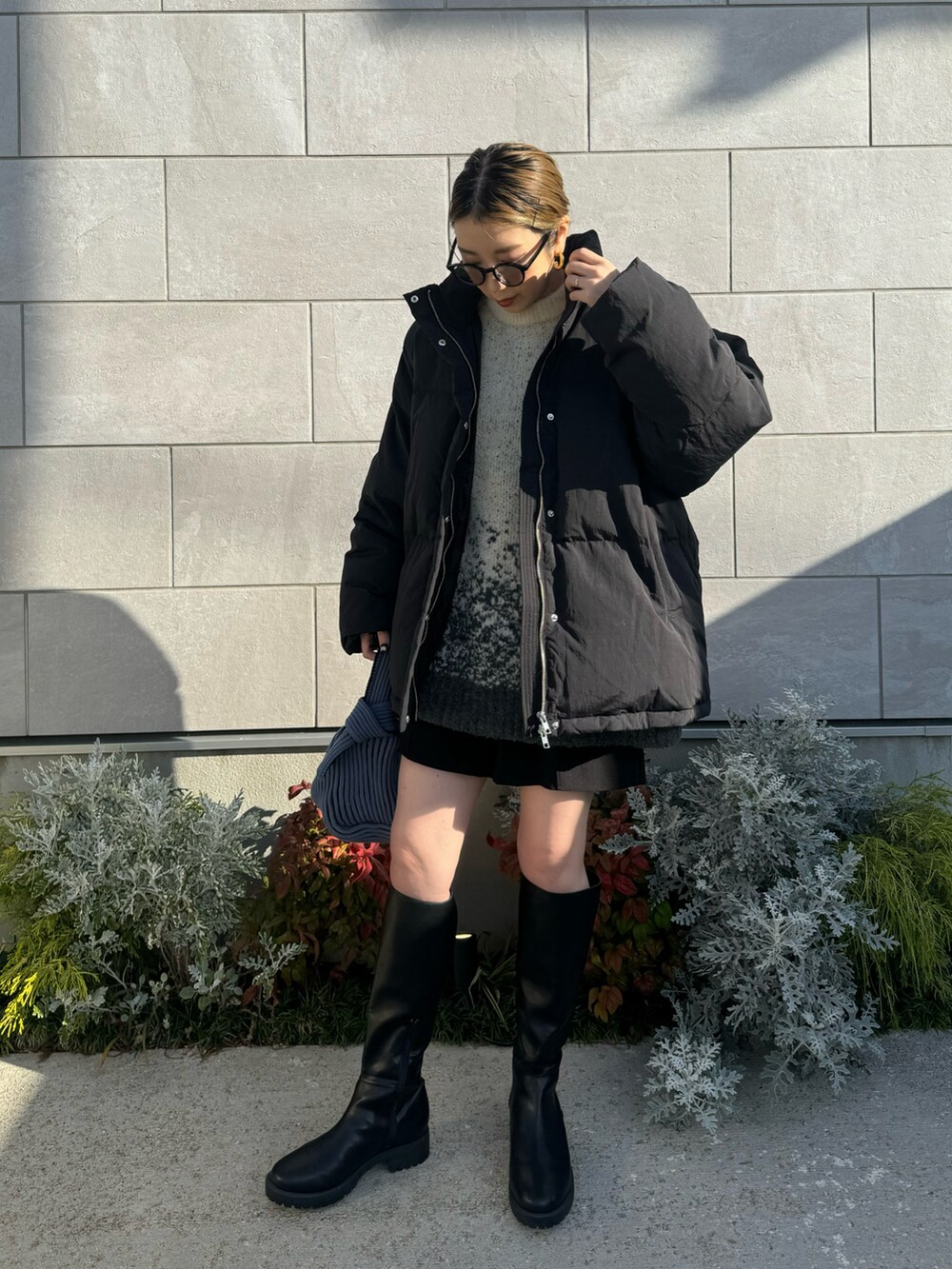 ブラック系のダウンジャケット/コート、ホワイト系のニット/セーター、ブルー系のハンドバッグを着用したレディースの冬コーディネートの4枚目の写真