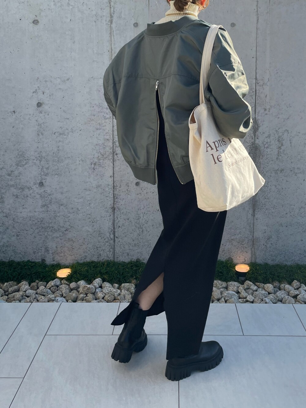 グリーン系のブルゾン、ホワイト系のニット/セーター、ブラック系のブーツを着用したレディースの秋コーディネートの3枚目の写真