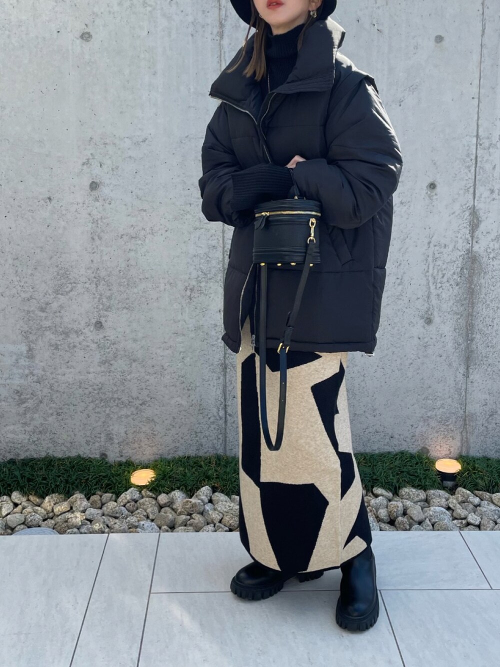 ブラック系のダウンジャケット/コート、ブラック系のブーツ、ブラック系のニット/セーターを着用したレディースの秋コーディネートの2枚目の写真