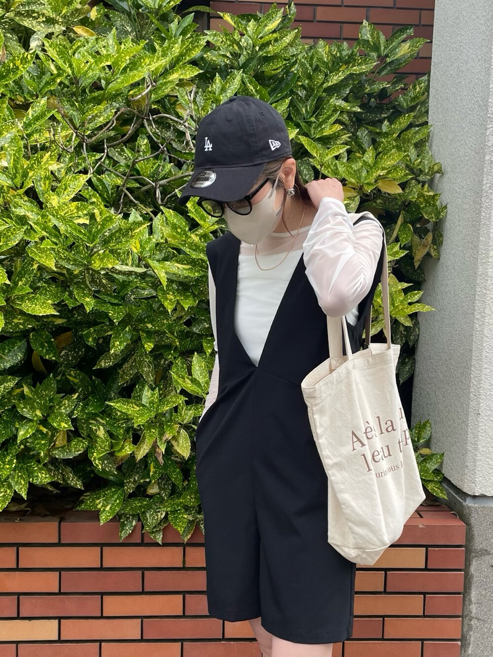 ブラック系のサロペット/オーバーオール、ホワイト系のTシャツ/カットソー、ホワイト系のサンダルを着用したレディースの春コーディネートの3枚目の写真