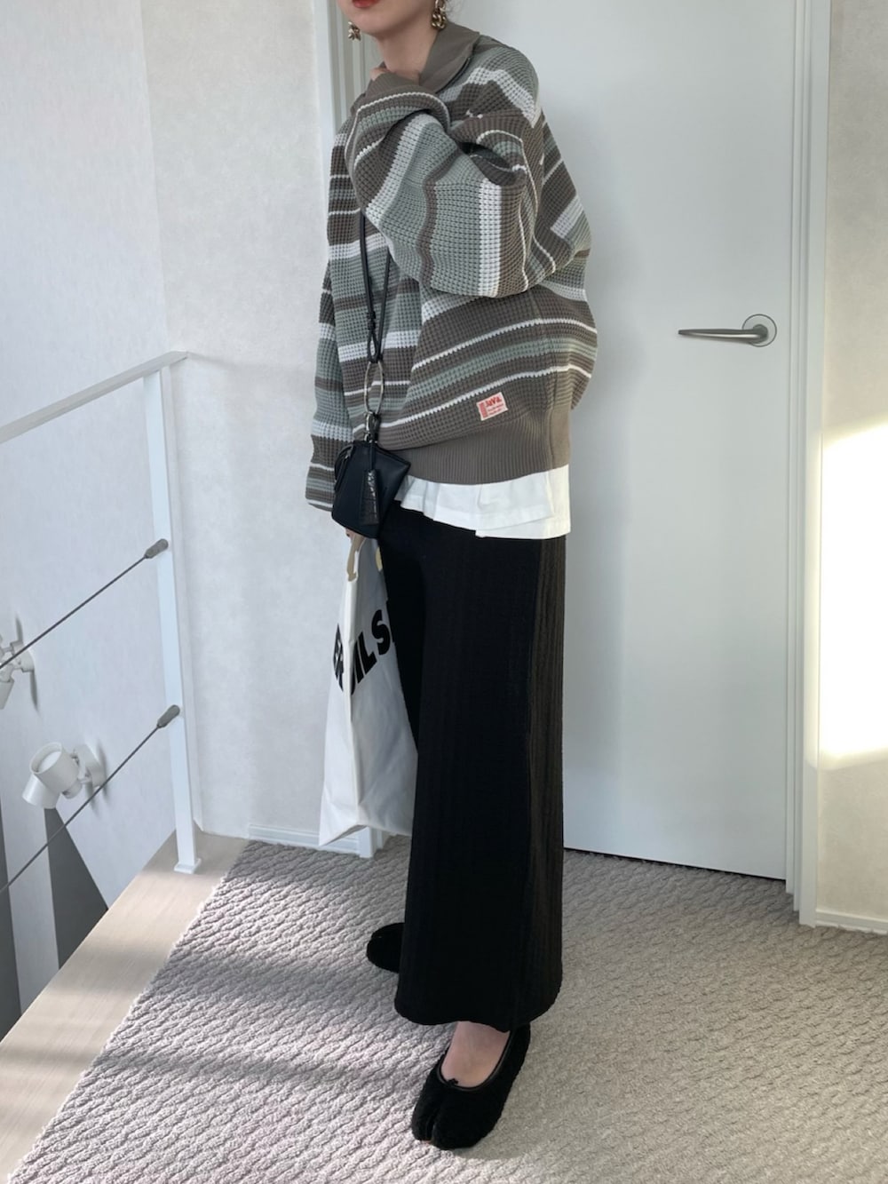 ブラック系のスカート、ブルー系のニット/セーター、ブラック系のショルダーバッグを着用したレディースの冬コーディネートの2枚目の写真