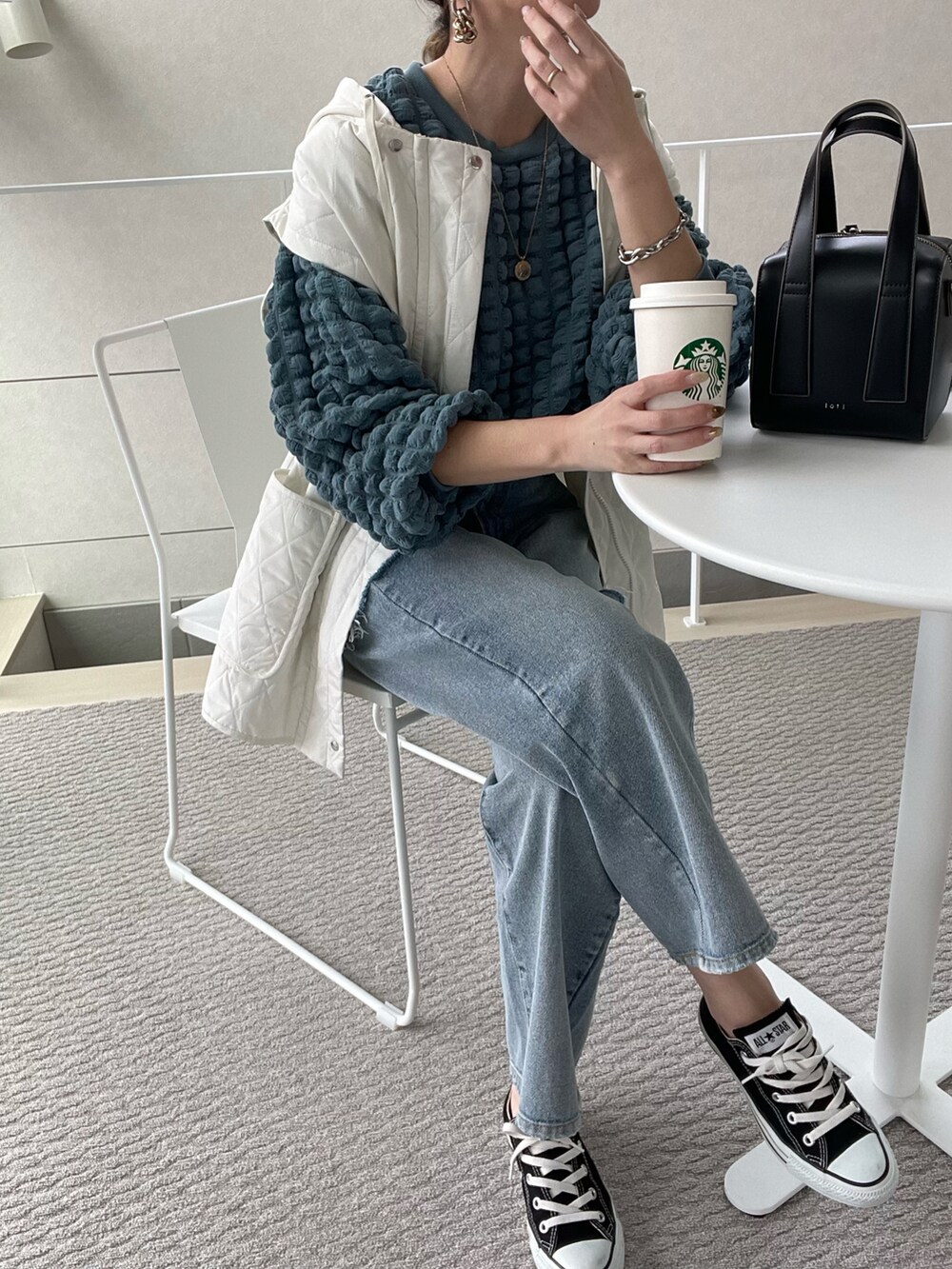 ブルー系のTシャツ/カットソー、ホワイト系のベスト、ブラック系のボストンバッグを着用したレディースの冬コーディネートの2枚目の写真