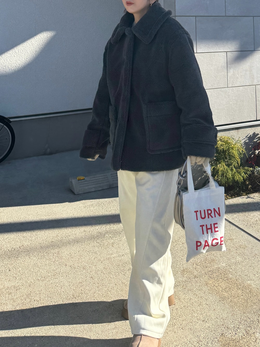 グレー系のステンカラーコート、ホワイト系のスウェットパンツ、ブラウン系のキャップを着用したレディースの冬コーディネートの3枚目の写真