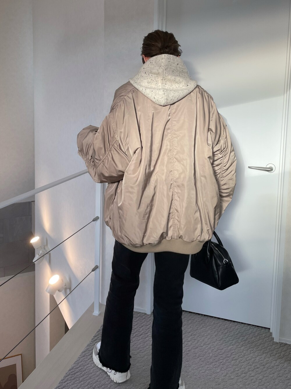 ベージュ系のMA-1、ホワイト系のスニーカー、ブラック系のボストンバッグを着用したレディースの冬コーディネートの5枚目の写真