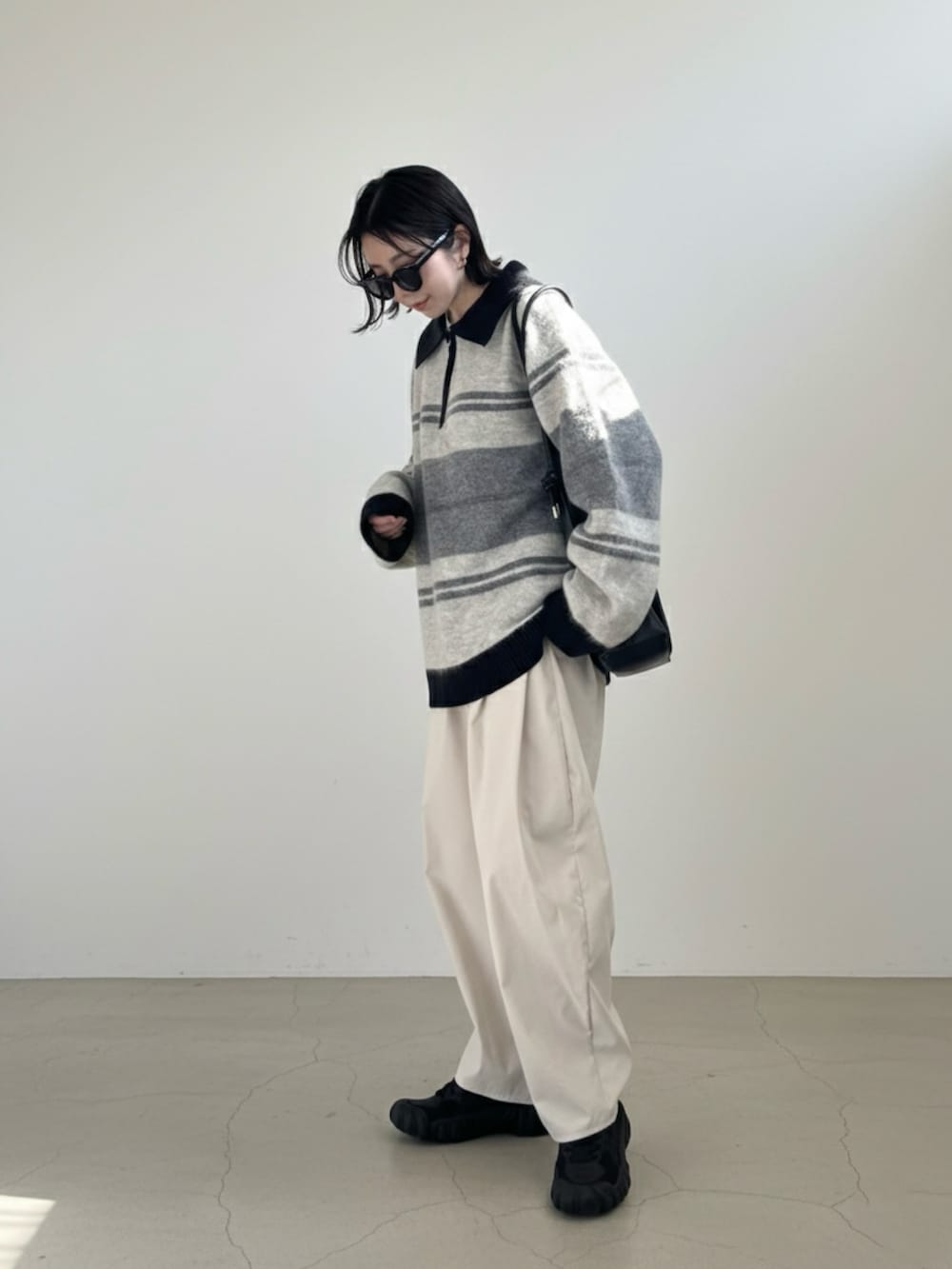 グレー系のニット/セーター、ホワイト系のチノパンツ、ブラック系のスニーカーを着用したレディースの冬コーディネートの2枚目の写真