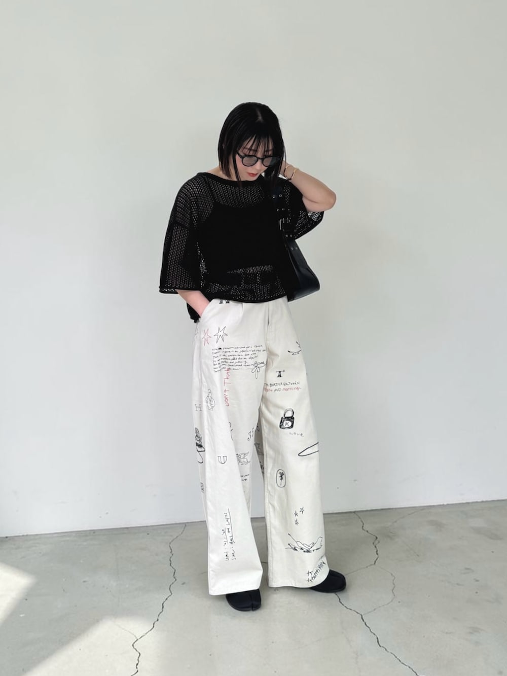ブラック系のニット/セーター、ブラック系のハンドバッグ、ブラック系のサンダルを着用したレディースの春コーディネートの2枚目の写真