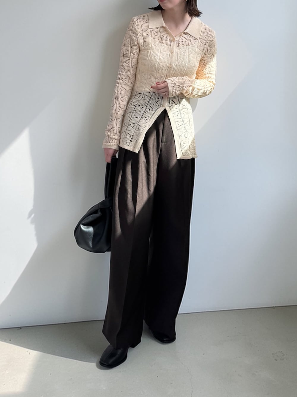 ブラウン系のその他パンツ、ホワイト系のニット/セーター、ブラック系のハンドバッグを着用したレディースの春コーディネートの2枚目の写真