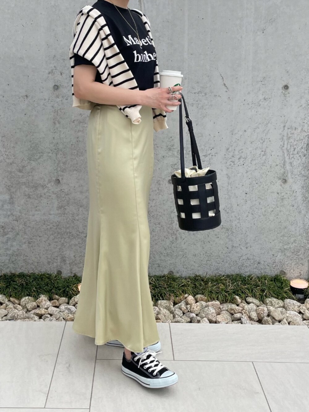 ブラック系のショルダーバッグ、イエロー系のスカート、ブラック系のスニーカーを着用したレディースの春コーディネートの2枚目の写真