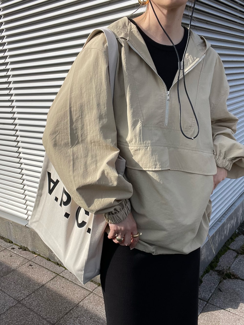 ベージュ系のナイロンジャケット、ブラック系のワンピース、ホワイト系のトートバッグを着用したレディースの秋コーディネートの5枚目の写真