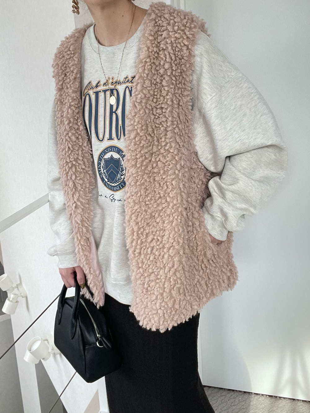 ベージュ系のベスト、ブラック系のスカート、ベージュ系のスウェットを着用したレディースの冬コーディネートの5枚目の写真