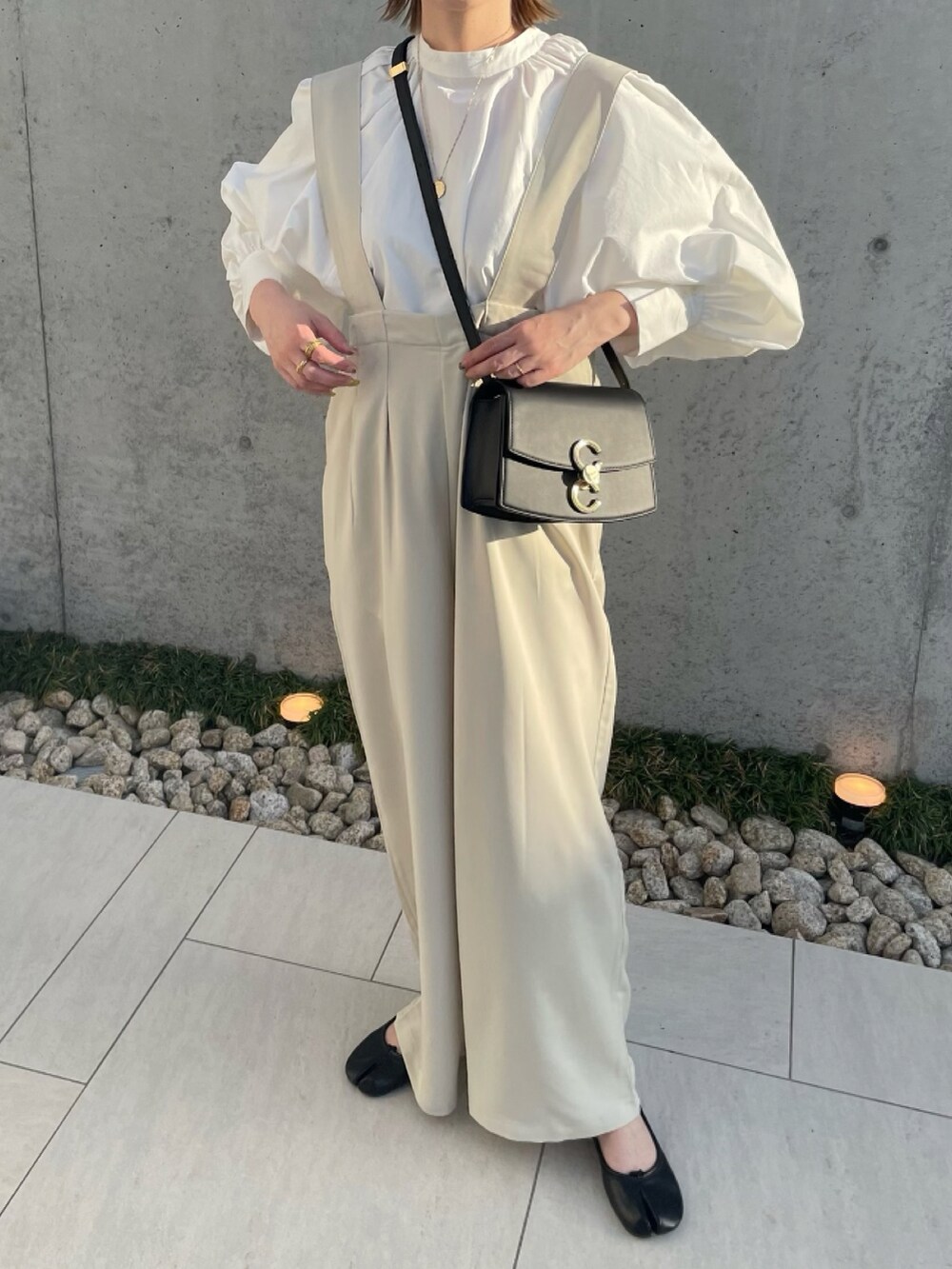 ホワイト系のサロペット/オーバーオール、ホワイト系のシャツ/ブラウス、ブラック系のパンプスを着用したレディースの春コーディネートの2枚目の写真