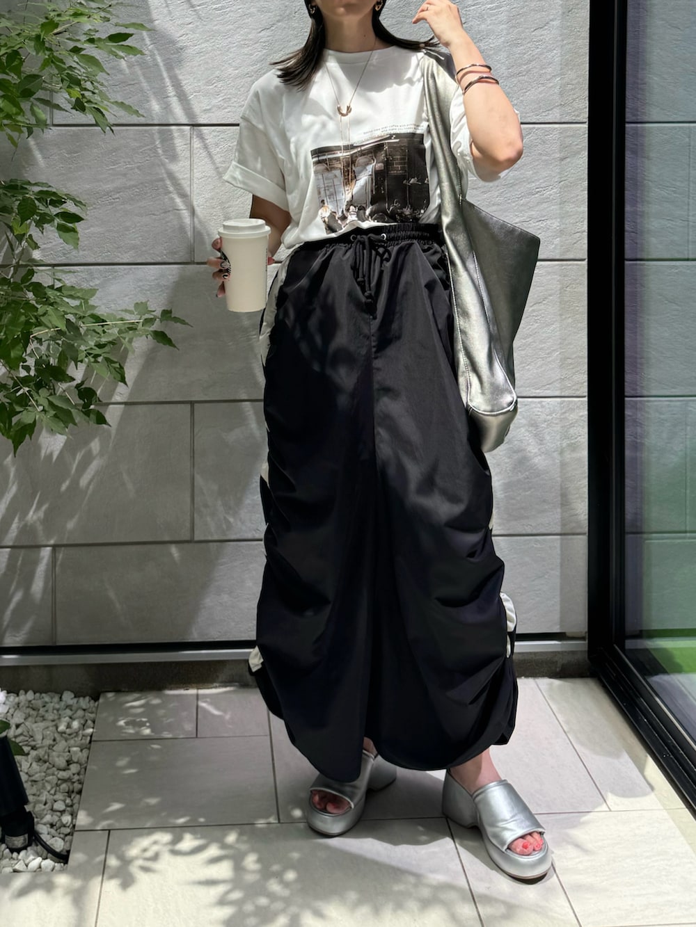 ブラック系のスカート、ホワイト系のTシャツ/カットソー、シルバー系のサンダルを着用したレディースの夏コーディネートの3枚目の写真