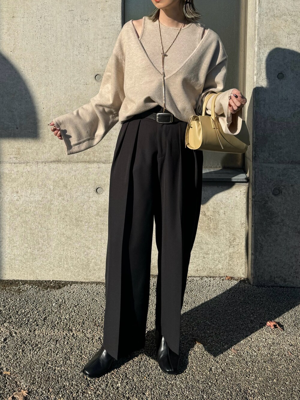 ベージュ系のニット/セーター、ブラック系のその他パンツ、ベージュ系のハンドバッグを着用したレディースの秋コーディネートの5枚目の写真