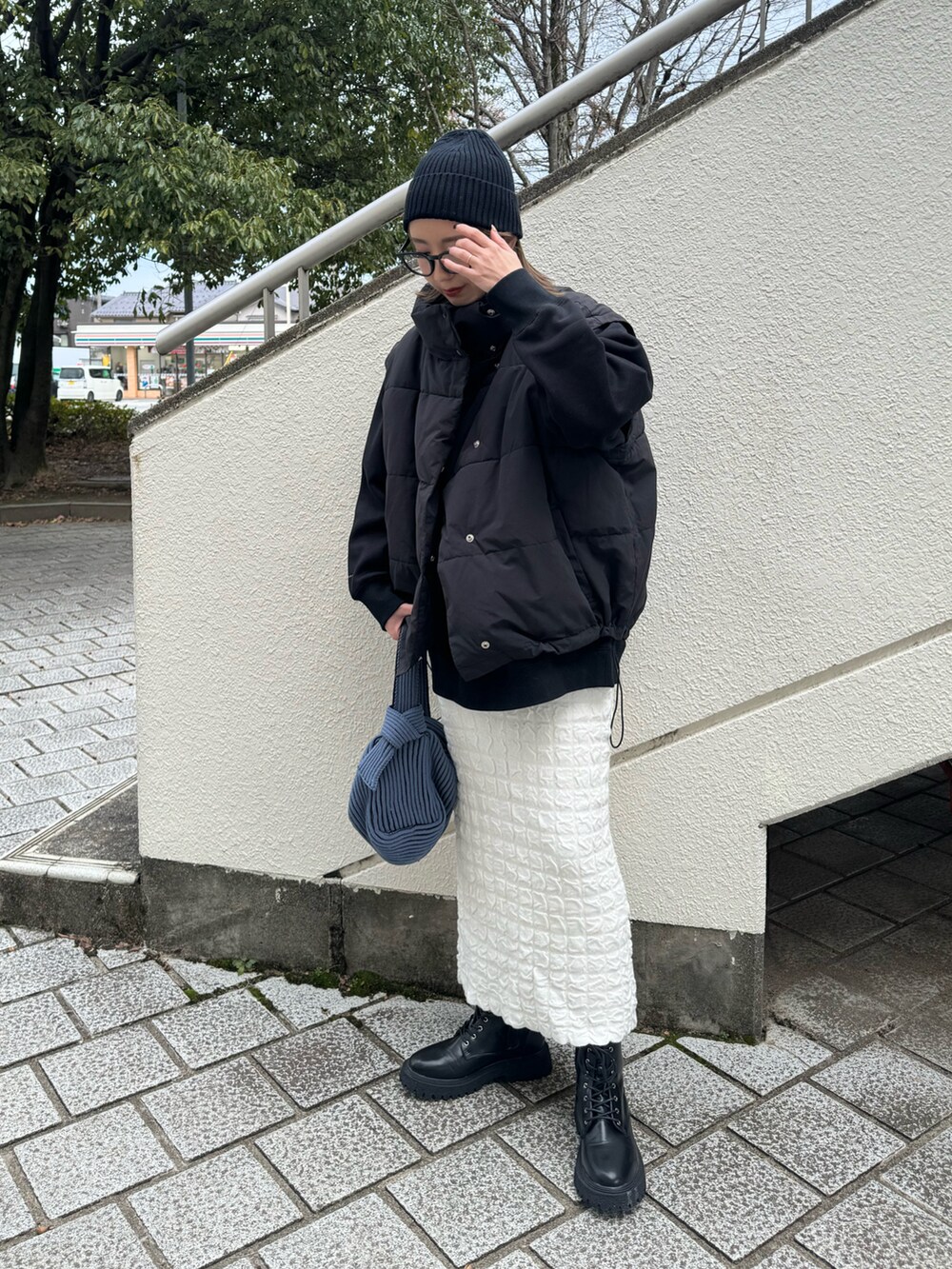 ブラック系のスウェット、ブラック系のブーツ、ブルー系のハンドバッグを着用したレディースの冬コーディネートの3枚目の写真