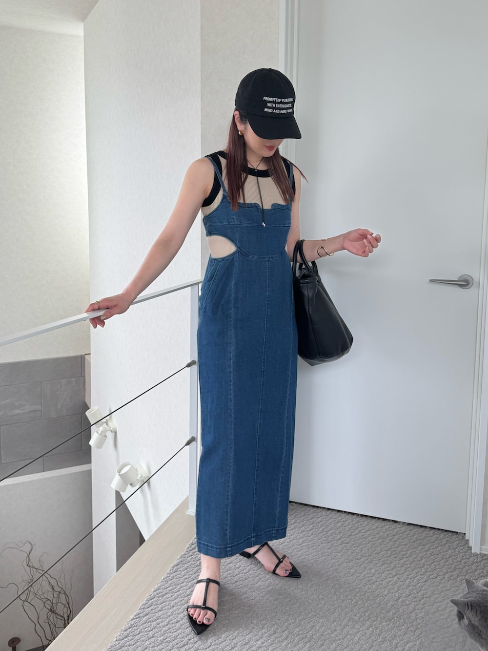 ブラック系のトートバッグ、ブルー系のジャンパースカート、ブラック系のサンダルを着用したレディースの夏コーディネートの2枚目の写真