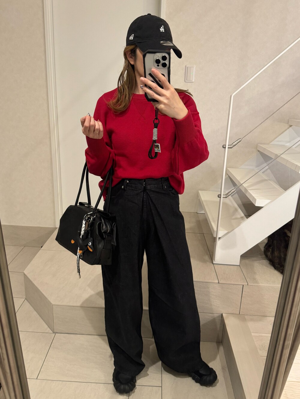 レッド系のニット/セーター、ブラック系のデニムパンツ、ブラック系のボストンバッグを着用したレディースの冬コーディネートの2枚目の写真