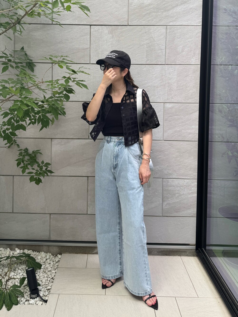 ブラック系のキャミソール、ブラック系のサンダル、ブルー系のデニムパンツを着用したレディースの夏コーディネートの3枚目の写真