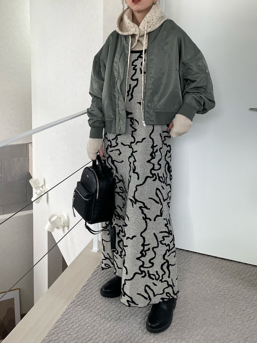 ブラック系のバックパック/リュック、ホワイト系のワンピース、グリーン系のブルゾンを着用したレディースの冬コーディネートの2枚目の写真