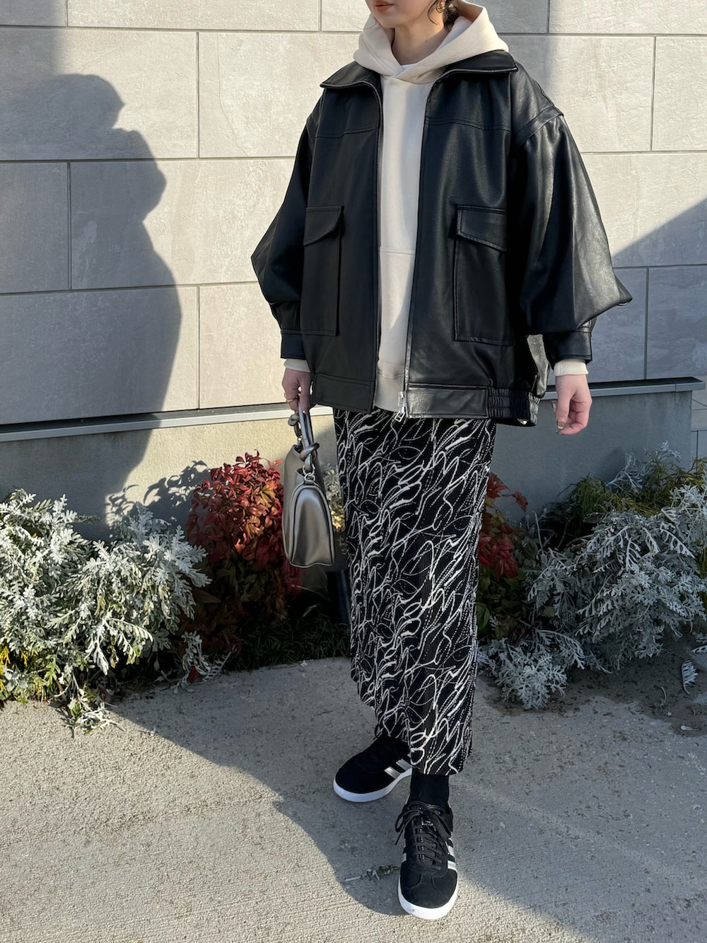 ブラック系のライダースジャケット、シルバー系のショルダーバッグ、ブラック系のスニーカーを着用したレディースの冬コーディネートの2枚目の写真