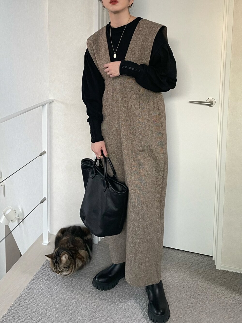 ブラウン系のジャンパースカート、ブラック系のTシャツ/カットソー、ブラック系のブーツを着用したレディースの冬コーディネートの2枚目の写真