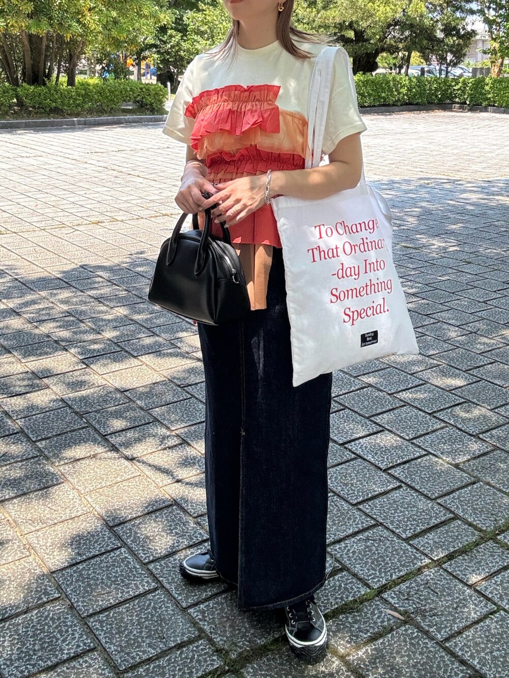 オレンジ系のTシャツ/カットソー、ブルー系のデニムスカート、ブラック系のスニーカーを着用したレディースの夏コーディネートの4枚目の写真