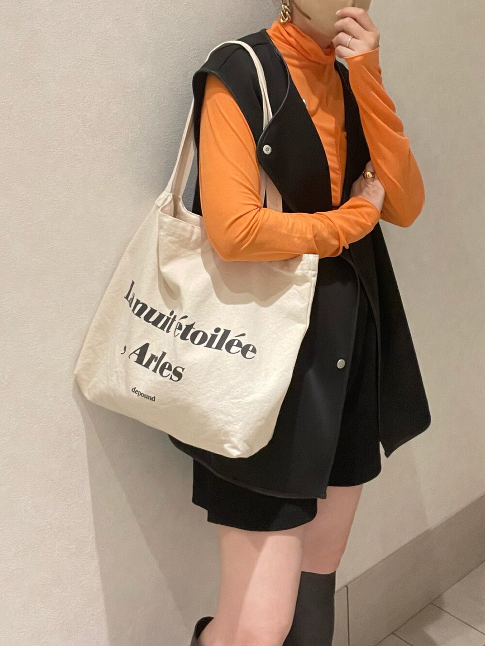 オレンジ系のTシャツ/カットソー、ブラック系のベスト、ブラウン系のブーツを着用したレディースの夏コーディネートの4枚目の写真