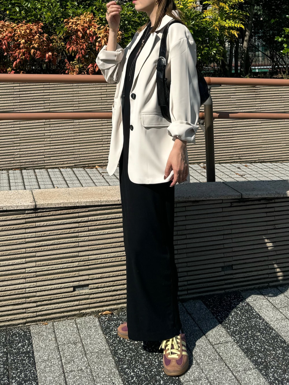 ホワイト系のテーラードジャケット、レッド系のスニーカー、ブラック系のワンピースを着用したレディースの秋コーディネートの5枚目の写真