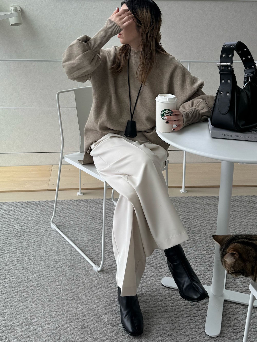 ブラック系のハンドバッグ、ベージュ系のニット/セーター、ホワイト系のその他パンツを着用したレディースの冬コーディネートの4枚目の写真