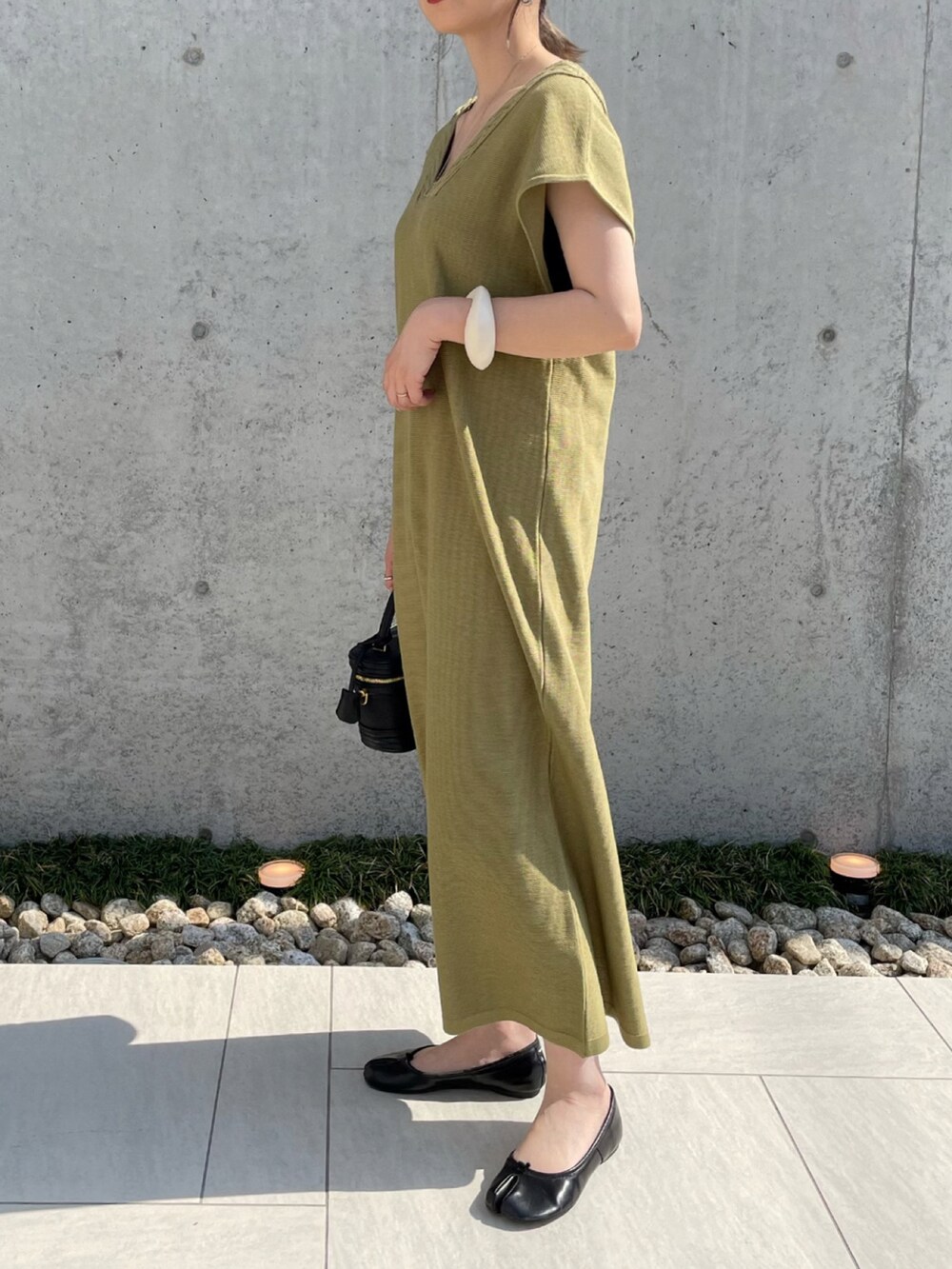 グリーン系のワンピース、ブラック系のパンプス、ホワイト系のブレスレットを着用したレディースの夏コーディネートの3枚目の写真