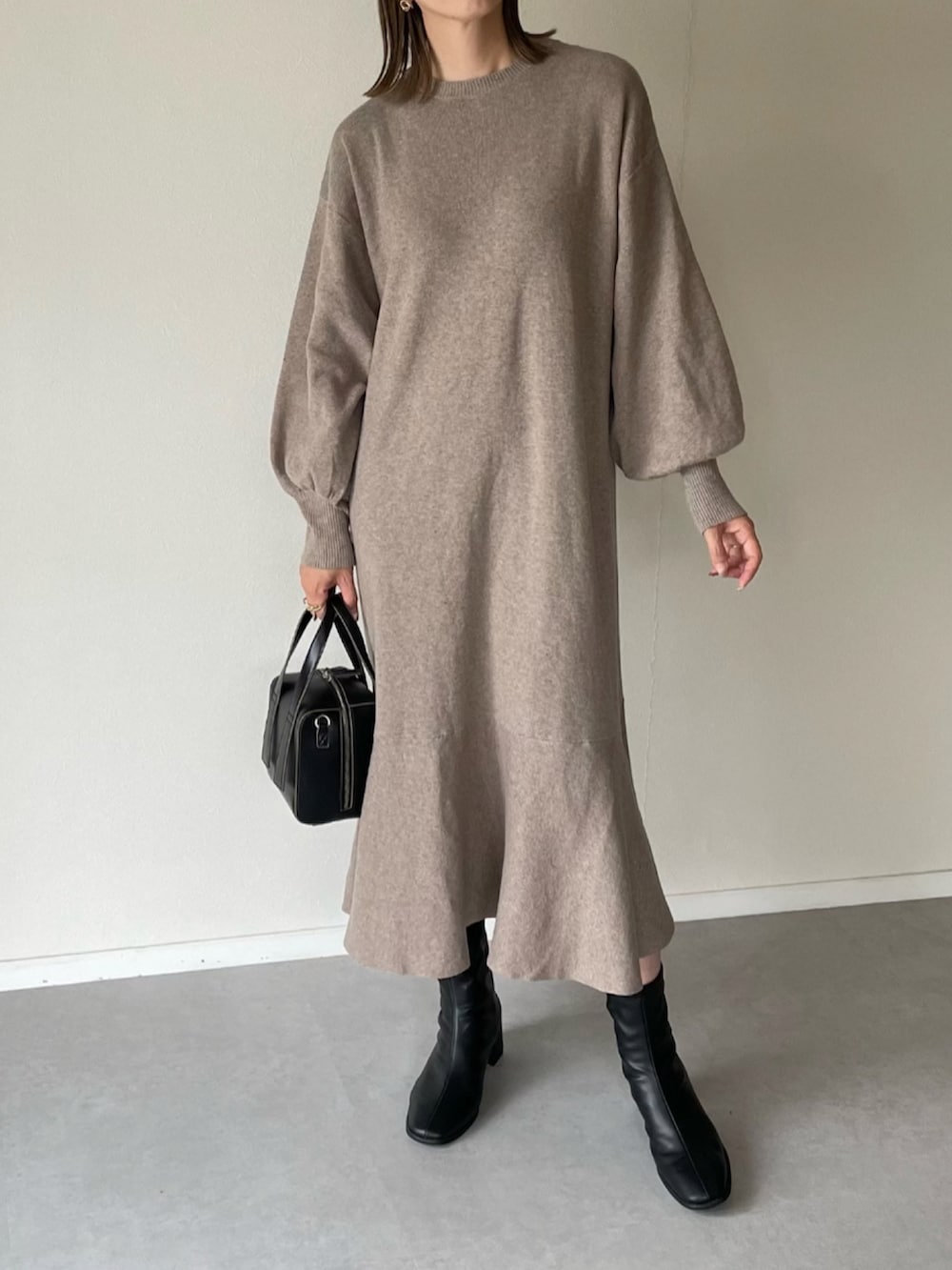 ホワイト系のベスト、ベージュ系のワンピース、ブラック系のボストンバッグを着用したレディースの秋コーディネートの5枚目の写真