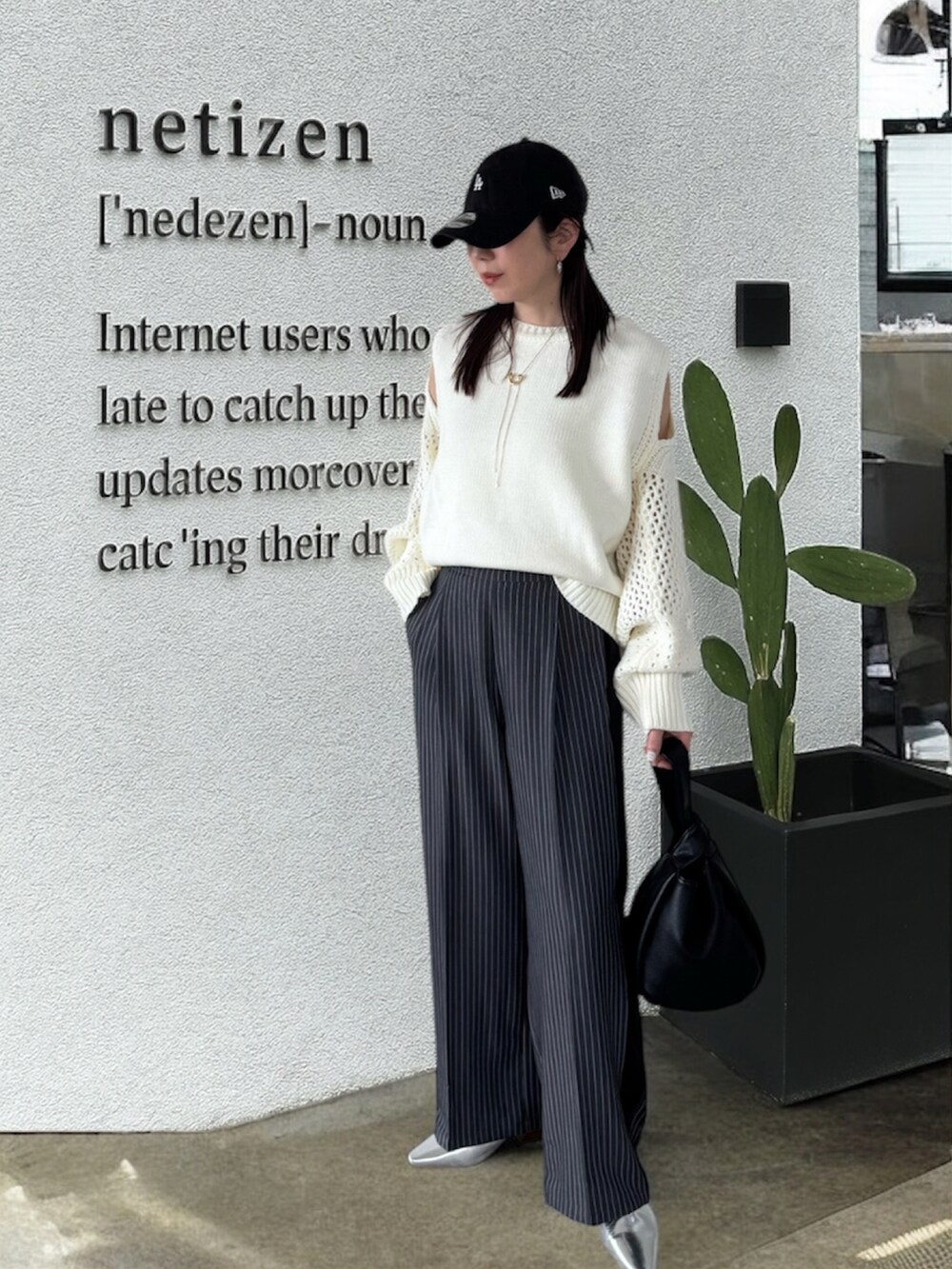 ホワイト系のニット/セーター、グレー系のスラックス、シルバー系のパンプスを着用したレディースの春コーディネートの2枚目の写真