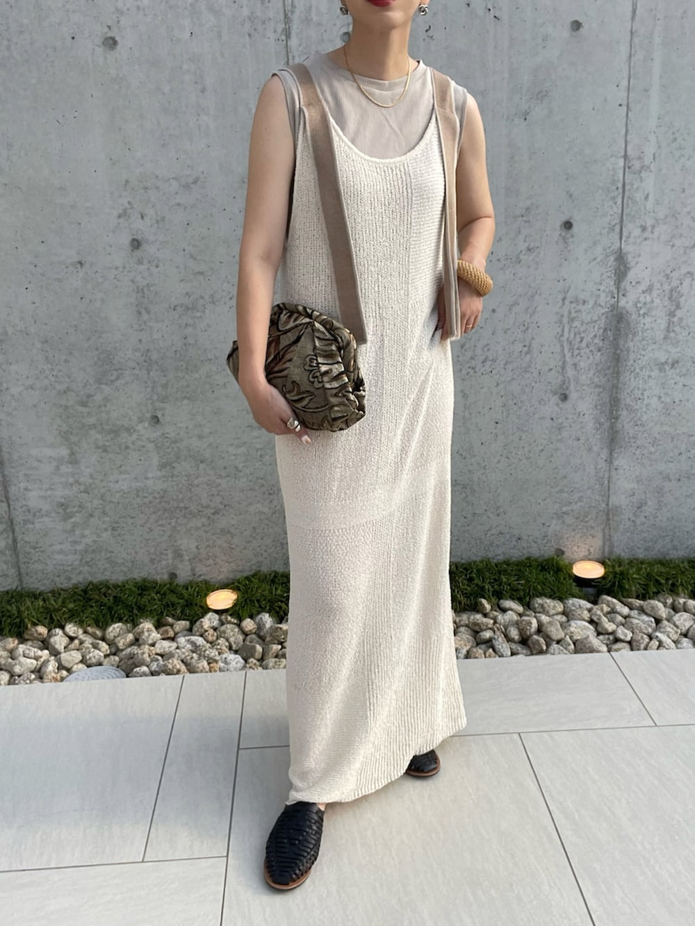 ホワイト系のワンピース、グリーン系のクラッチバッグ、ブラック系のサンダルを着用したレディースの夏コーディネートの2枚目の写真