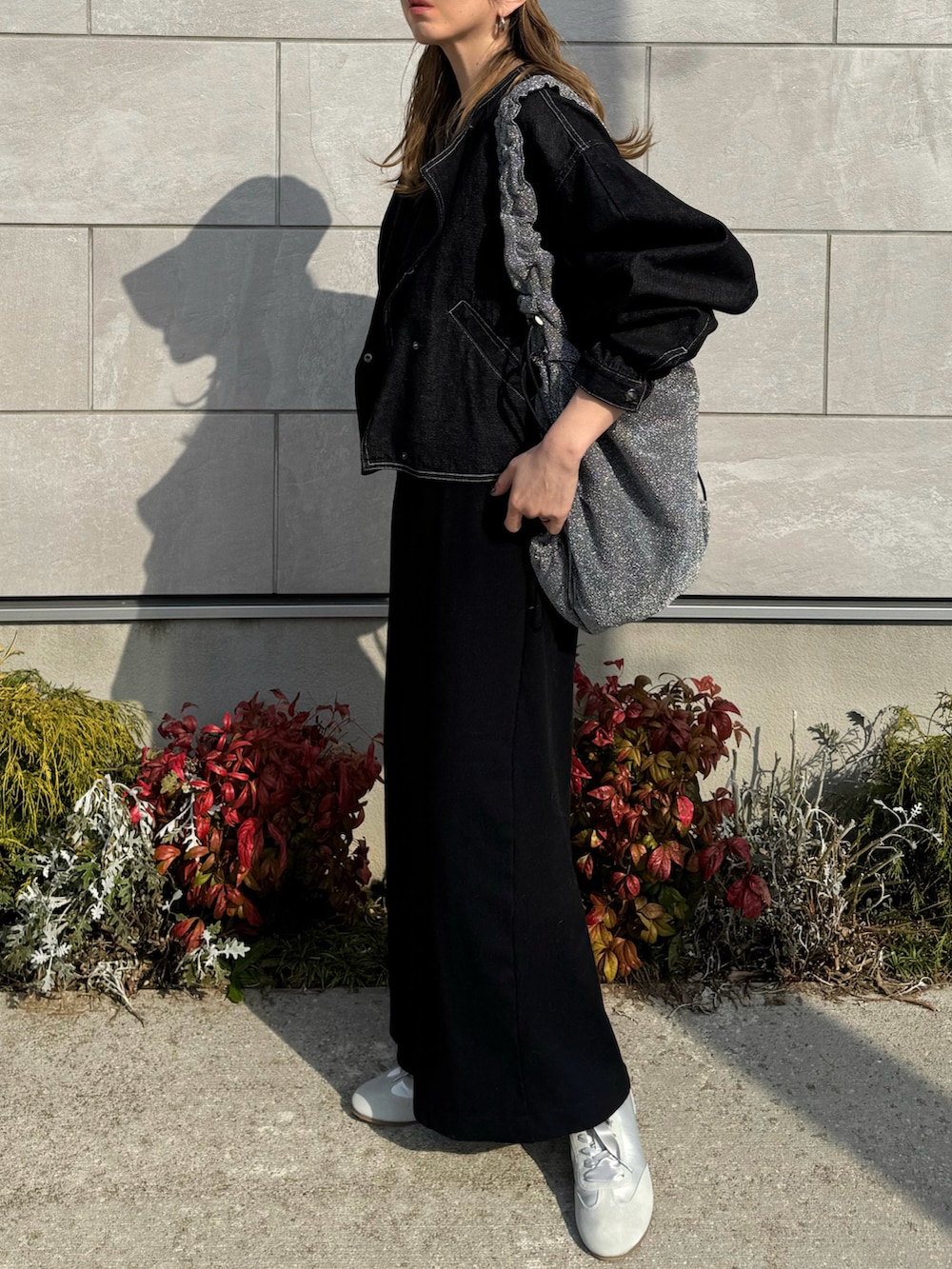 グレー系のスニーカー、ブラック系のワンピース、ブラック系のデニムジャケットを着用したレディースの春コーディネートの2枚目の写真