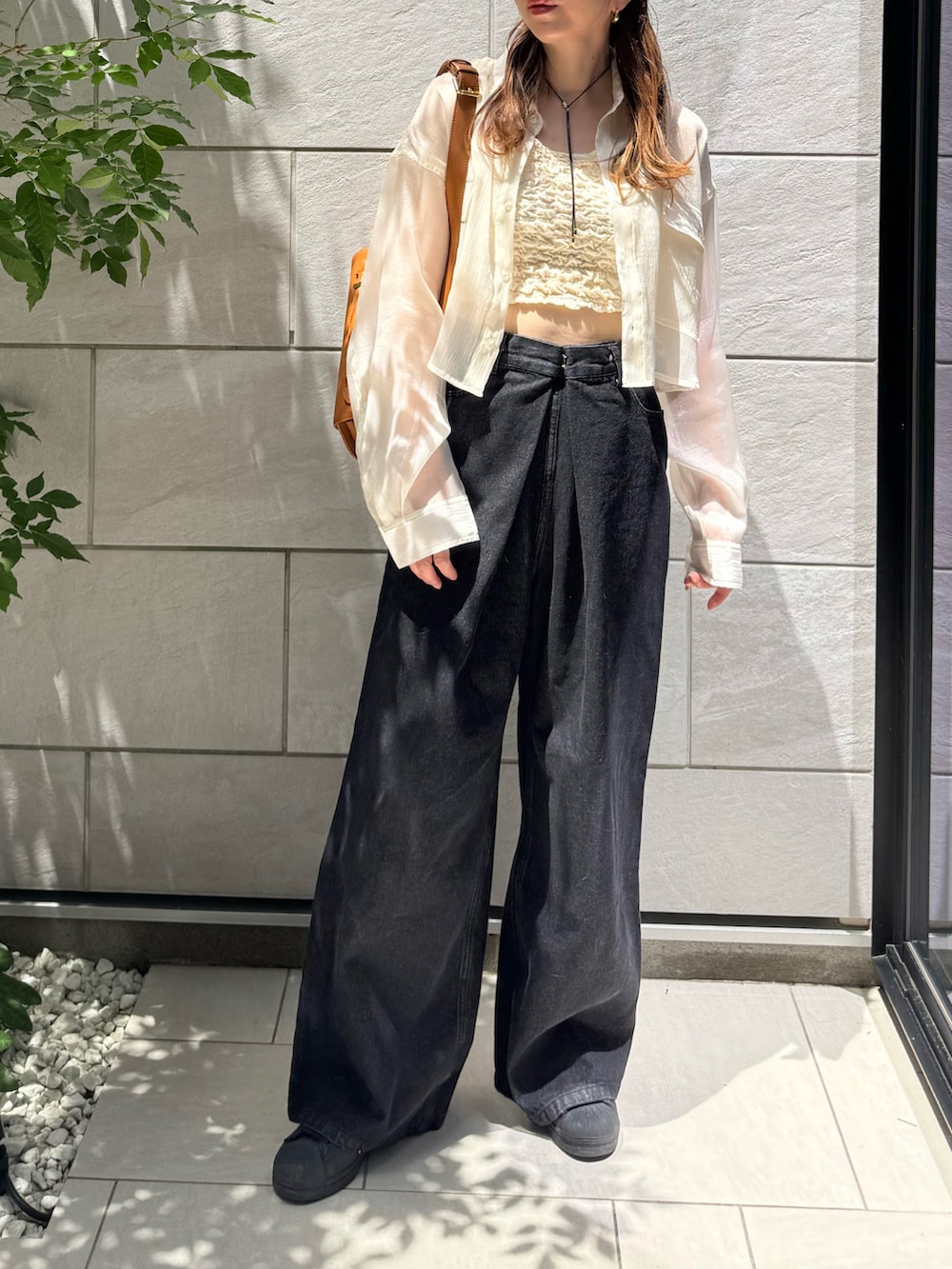 ホワイト系のタンクトップ、ブラック系のデニムパンツ、ブラック系のスニーカーを着用したレディースの夏コーディネートの4枚目の写真