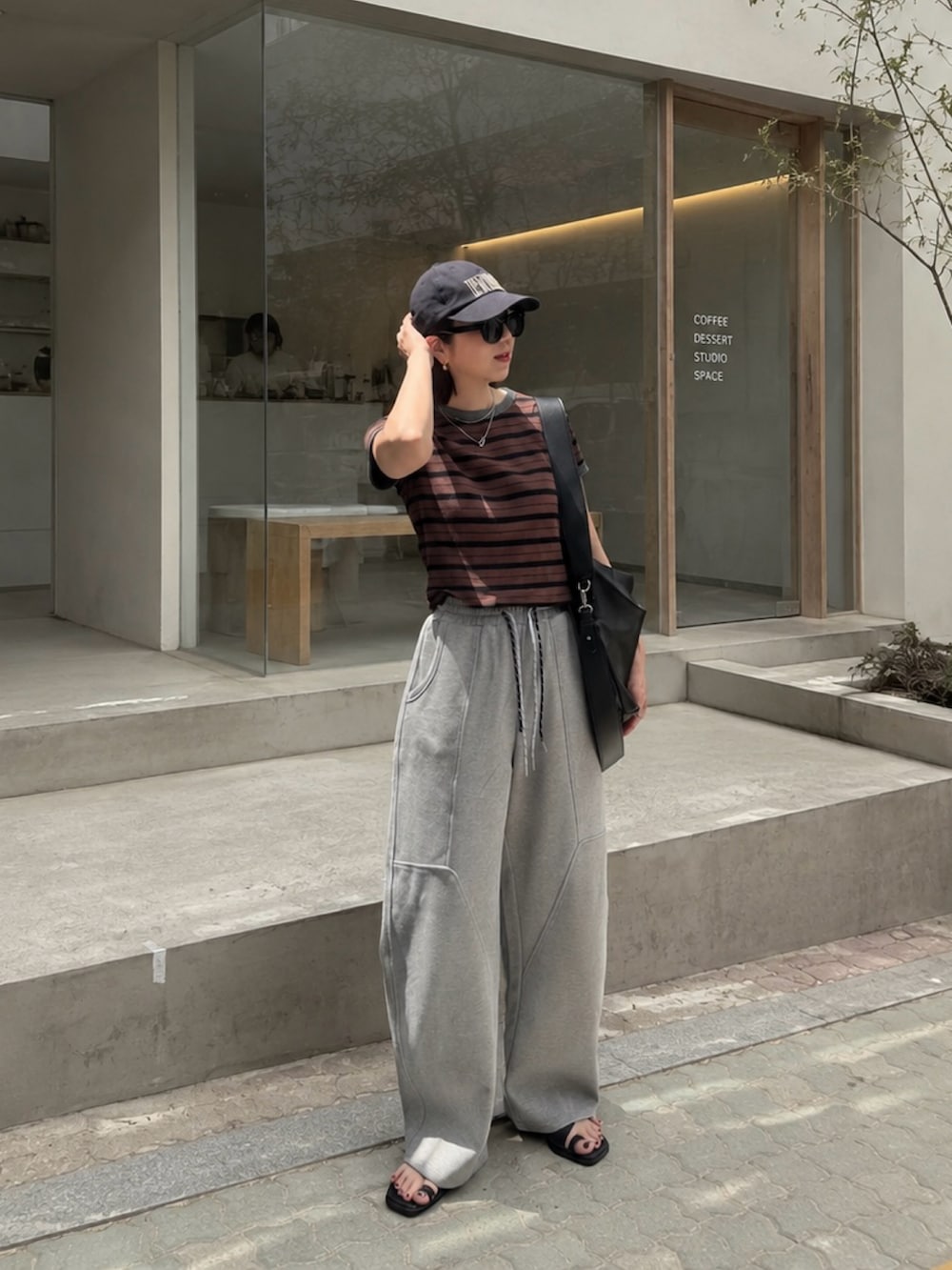 ブラウン系のTシャツ/カットソー、グレー系のスウェットパンツ、ブラック系のショルダーバッグを着用したレディースの夏コーディネートの2枚目の写真