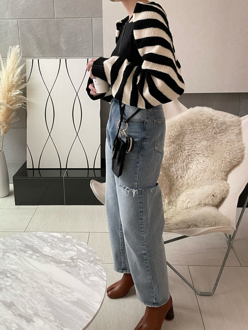 ブラック系のニット/セーター、ブラウン系のブーツ、ブラック系のショルダーバッグを着用したレディースの冬コーディネートの4枚目の写真