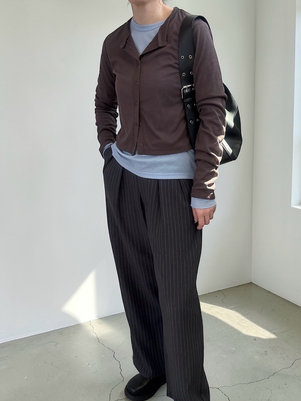 ブラウン系のカーディガン/ボレロ、グレー系のスラックス、ブラック系のハンドバッグを着用したレディースの春コーディネートの3枚目の写真