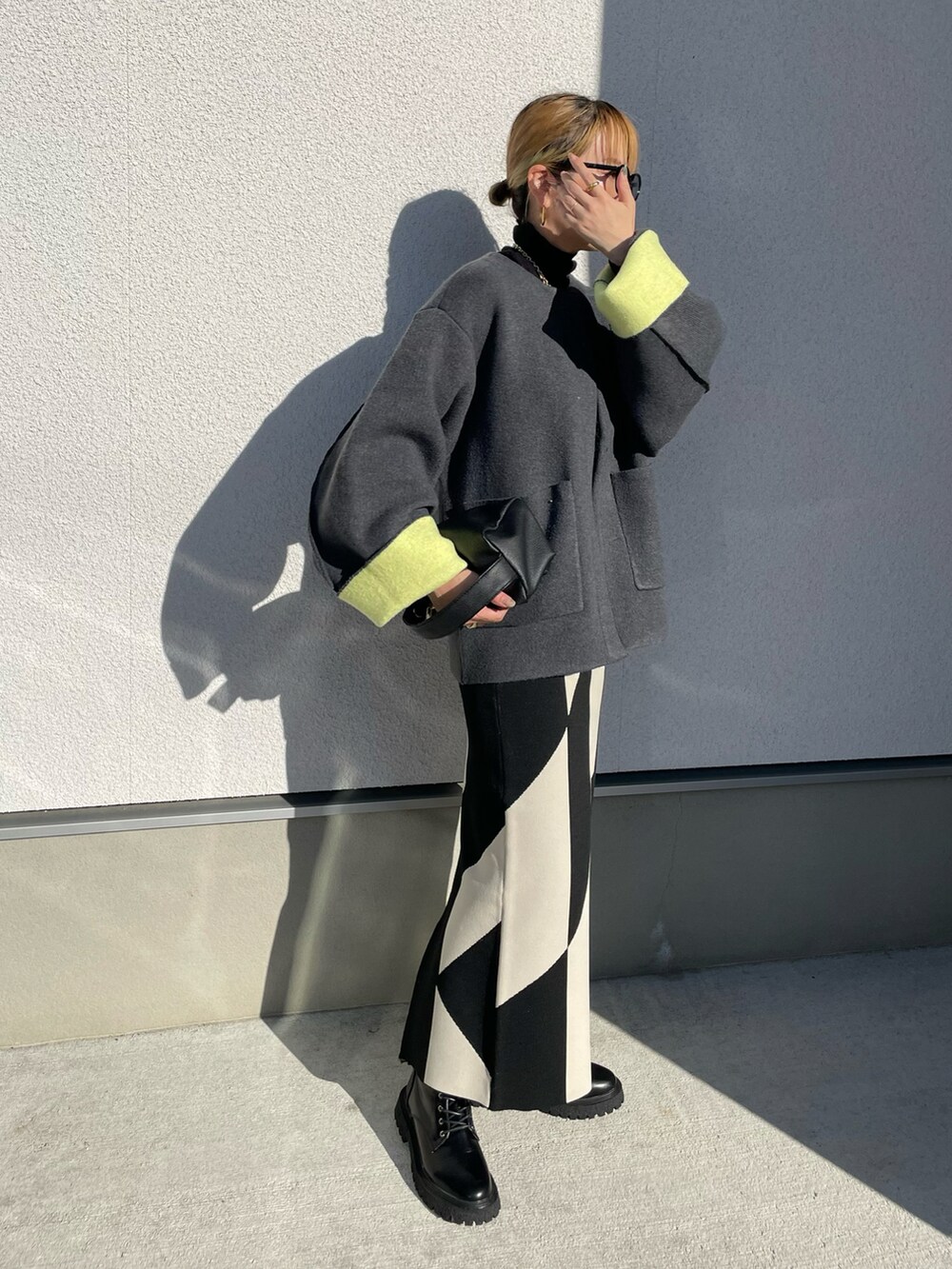 グレー系のノーカラーコート、ブラック系のブーツ、ブラック系のニット/セーターを着用したレディースの秋コーディネートの4枚目の写真