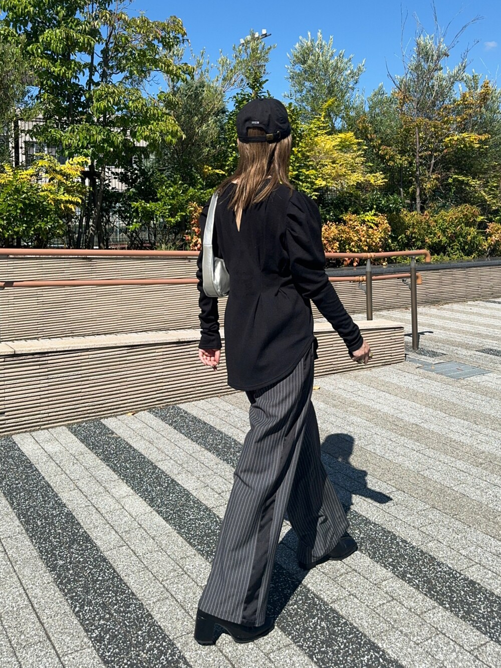 ブラック系のTシャツ/カットソー、シルバー系のショルダーバッグ、グレー系のスラックスを着用したレディースの秋コーディネートの2枚目の写真