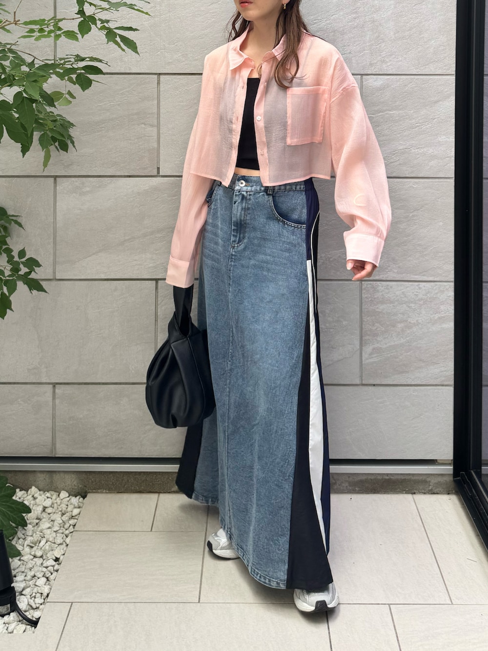 ブラック系のハンドバッグ、ブルー系のスカート、グレー系のスニーカーを着用したレディースの夏コーディネートの2枚目の写真