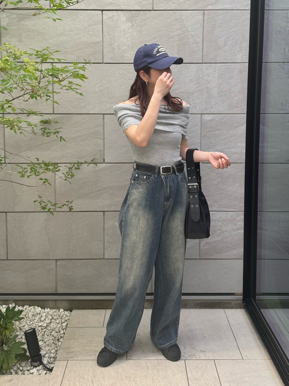 グレー系のニット/セーター、ブルー系のデニムパンツ、ブラック系のハンドバッグを着用したレディースの春コーディネートの2枚目の写真