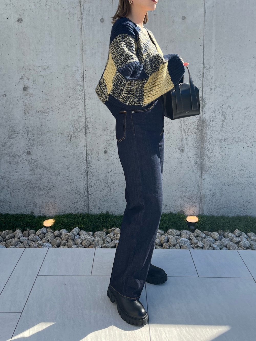 ブルー系のニット/セーター、ブラック系のボストンバッグ、ブルー系のデニムパンツを着用したレディースの秋コーディネートの4枚目の写真