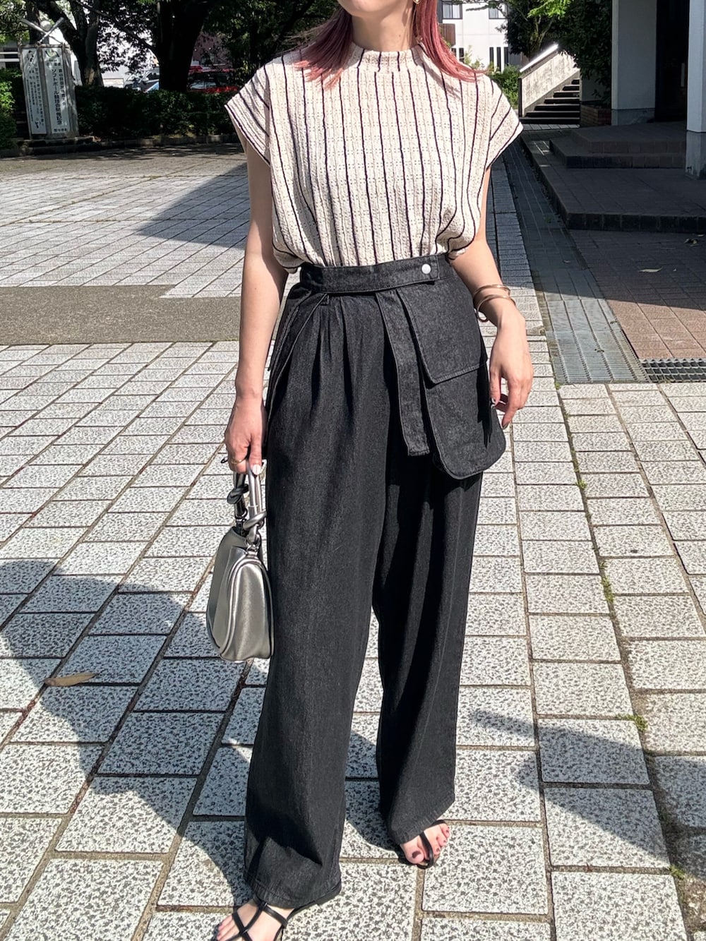 ブラック系のデニムパンツ、ブラック系のサンダル、シルバー系のショルダーバッグを着用したレディースの春コーディネートの3枚目の写真