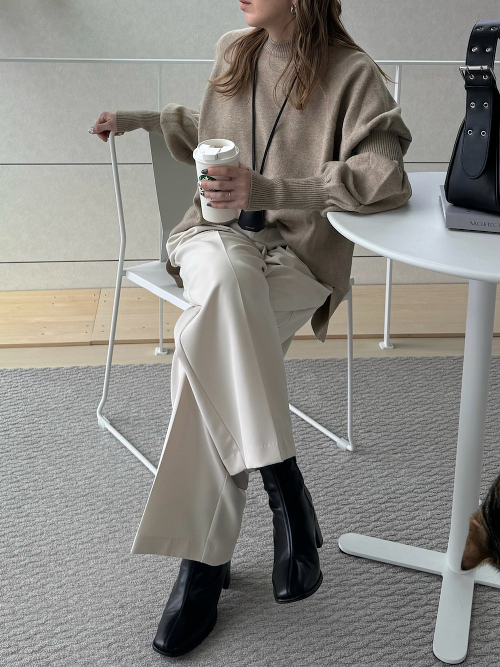 ブラック系のハンドバッグ、ベージュ系のニット/セーター、ホワイト系のその他パンツを着用したレディースの冬コーディネートの2枚目の写真