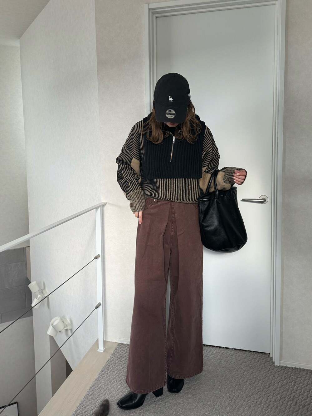 ブラック系のニット/セーター、ブラウン系のデニムパンツ、ブラック系のトートバッグを着用したレディースの冬コーディネートの3枚目の写真