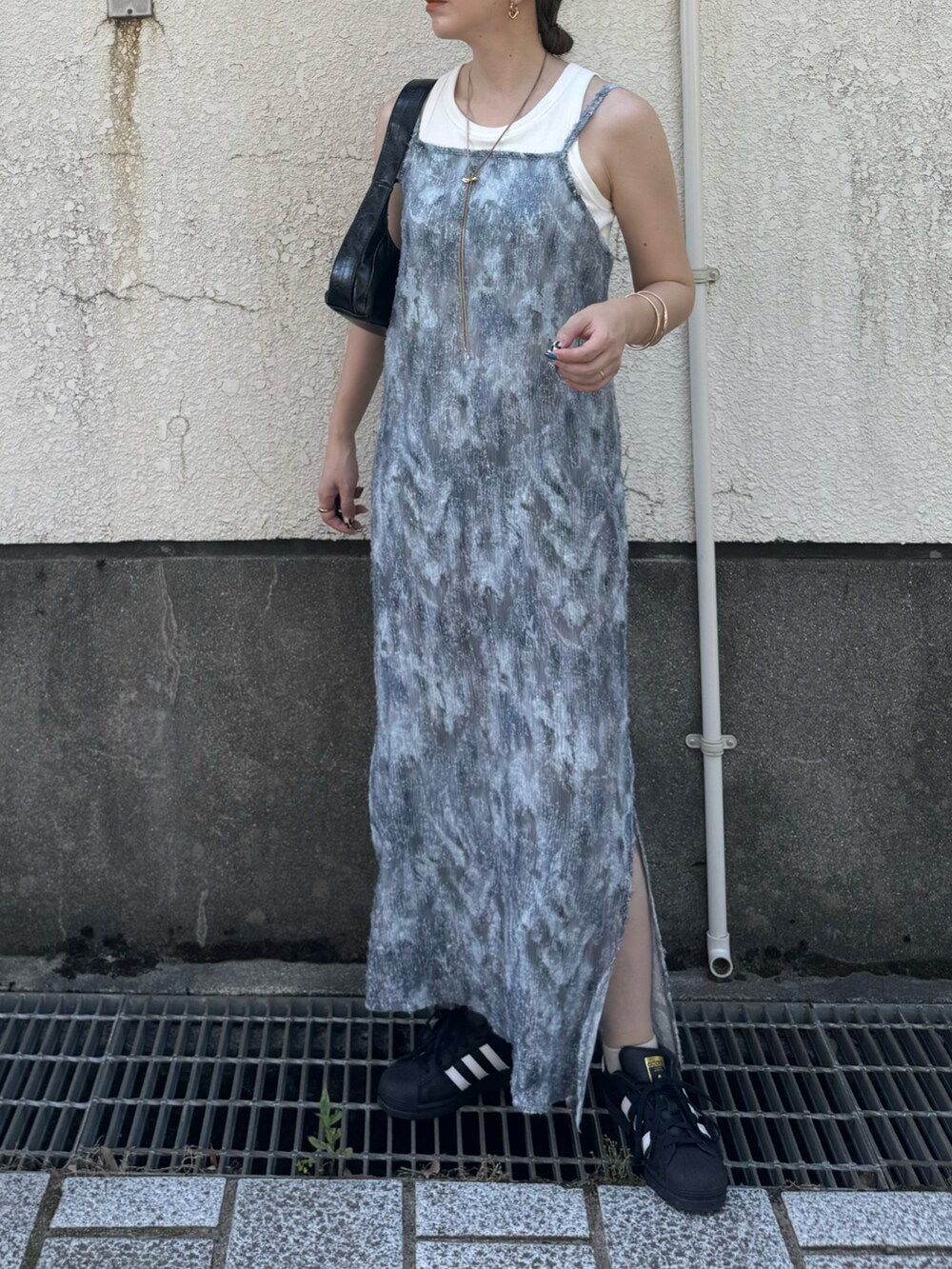 グレー系のワンピース、ブラック系のスニーカー、ブラック系のショルダーバッグを着用したレディースの夏コーディネートの3枚目の写真
