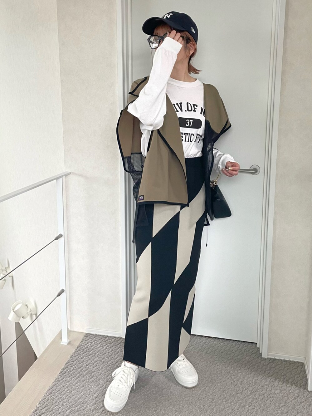 グリーン系のベスト、ホワイト系のTシャツ/カットソー、ホワイト系のスニーカーを着用したレディースの春コーディネートの3枚目の写真